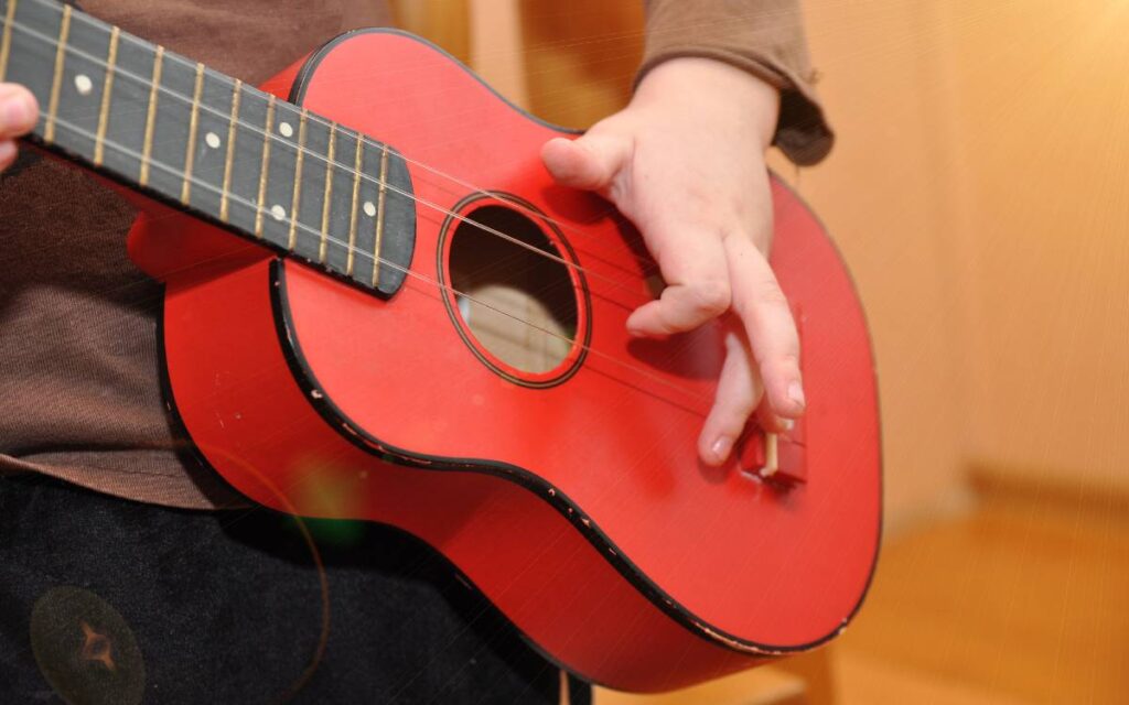 Closeup of child's hands playing toy ukulele