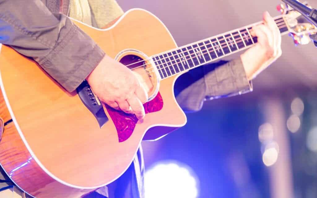 Cropped shot of a male musician playing an acoustic guitar on stage