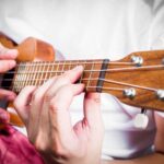 Male hands playing ukulele