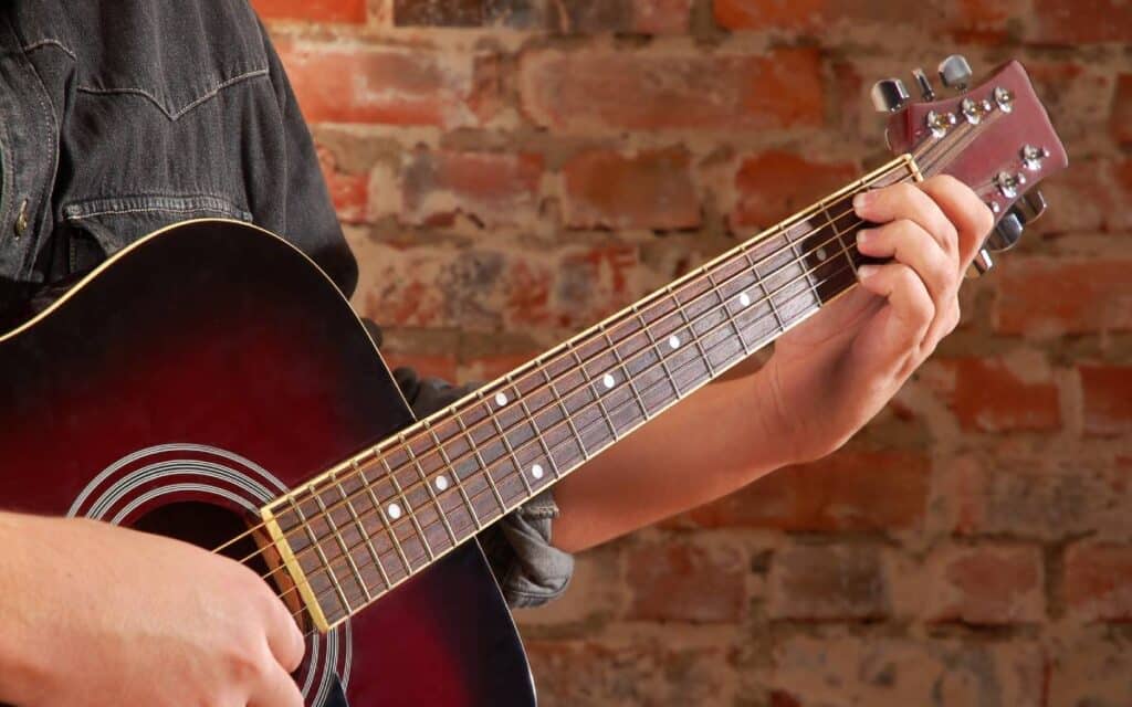 Hand on the neck of an acoustic guitar 1200x750