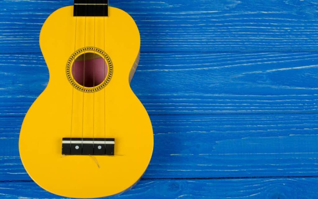 Body of a bright yellow ukulele on blue background