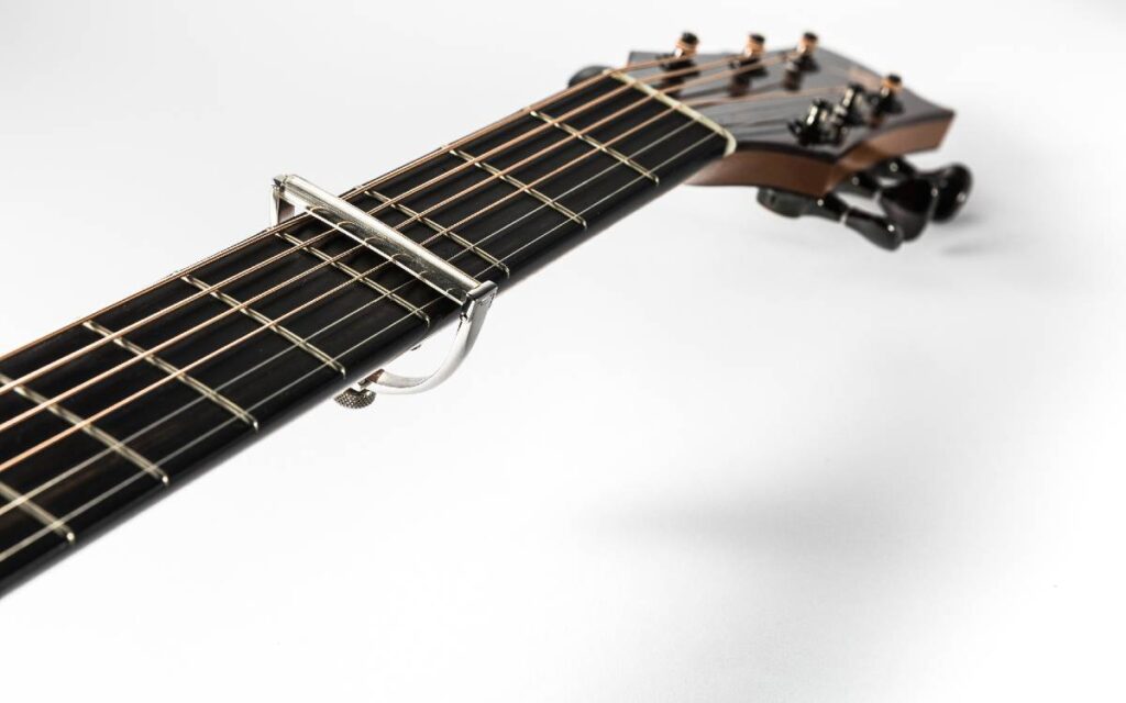 Acoustic guitar neck with capo on white background