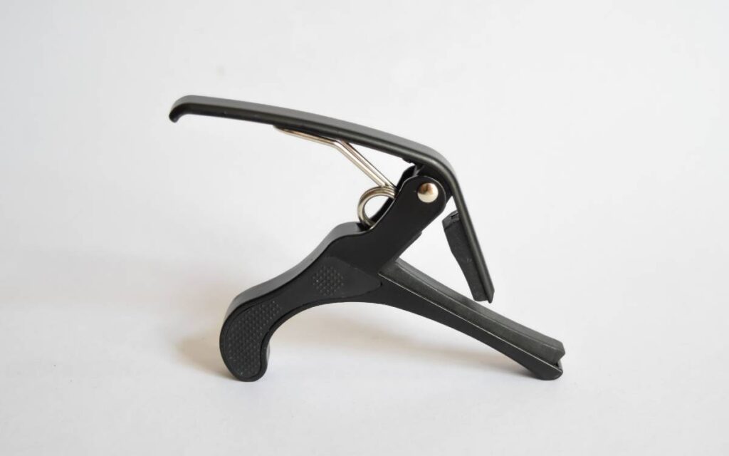 Black guitar capo on white background