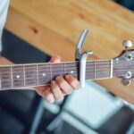 Cropped photo of a man playing acoustic guitar with capo