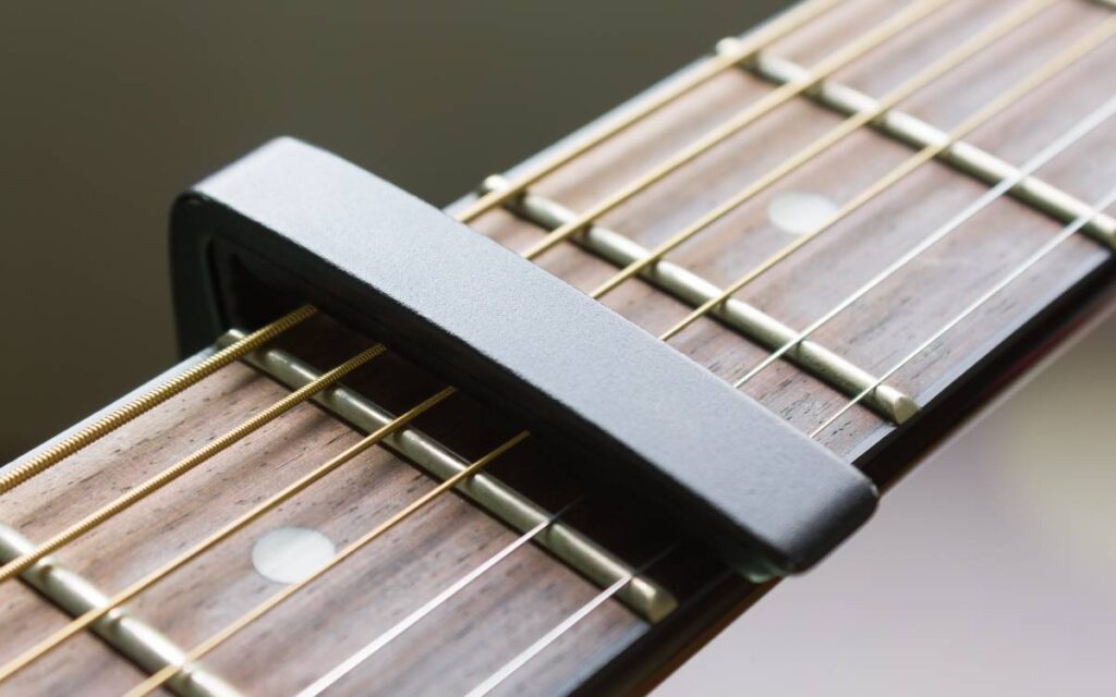 One of the best guitar capos clamped onto an acoustic guitar strings and fingerboard