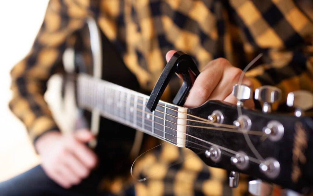 Man installing capo on acoustic guitar