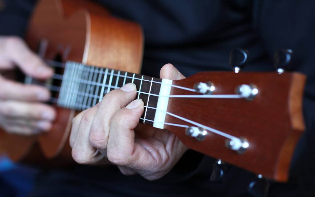 Man playing a chord on a ukulele