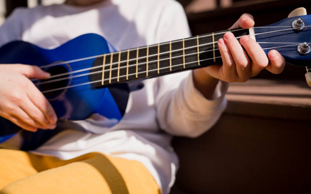 Boy playing a blue ukulele