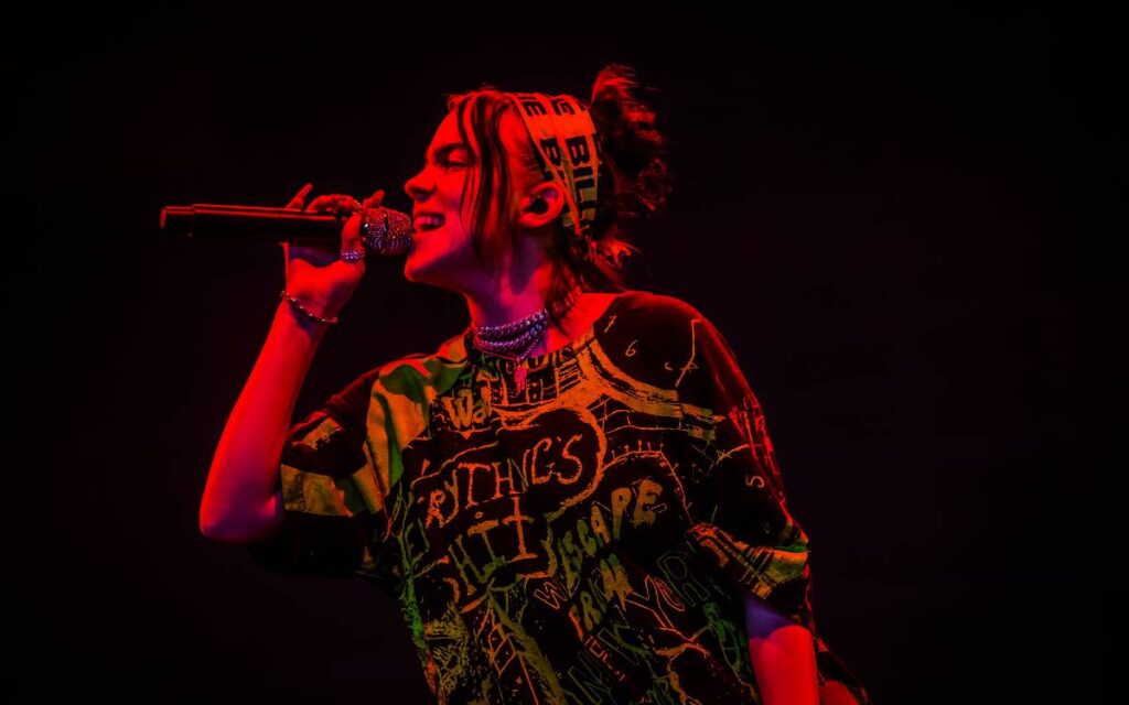 Billie eilish singing on stage on dark background